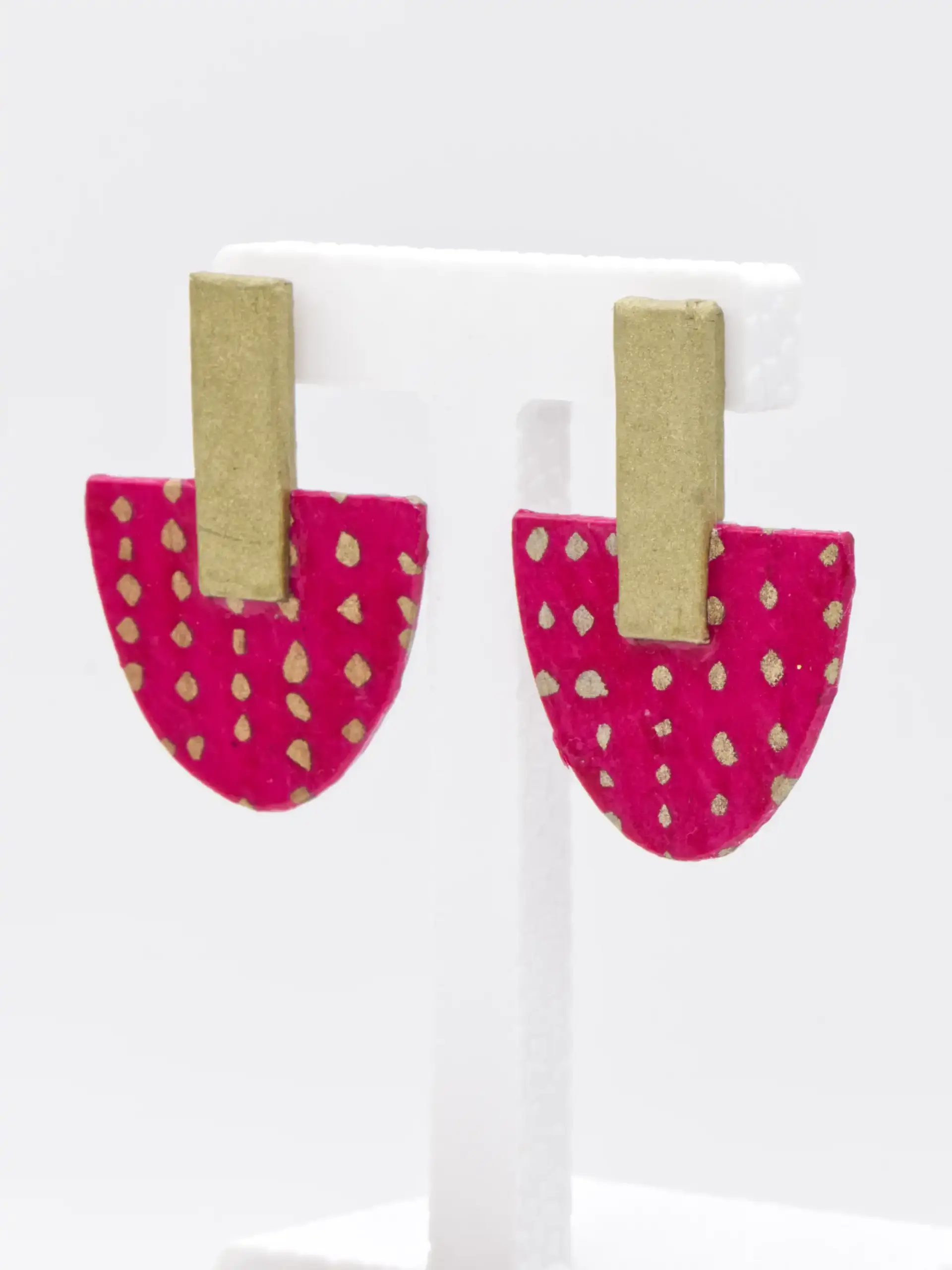 Pink and gold heart-shaped earrings on white display