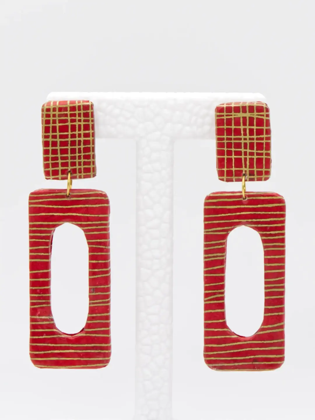 Red and gold geometric drop earrings on white stand