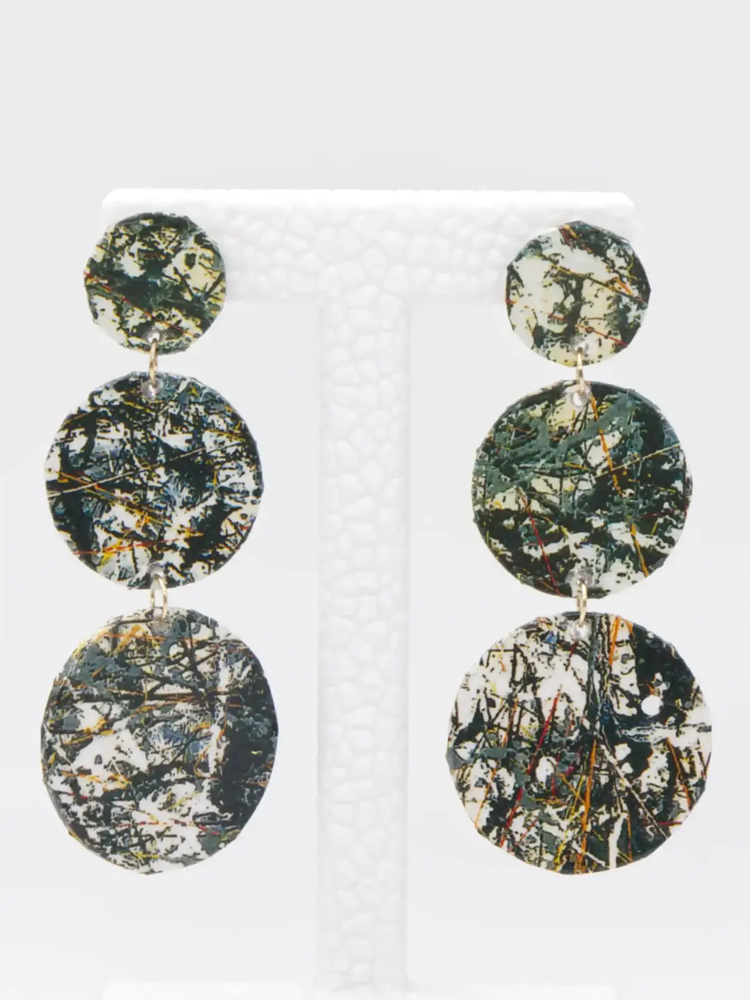 Three-tier marbled circular drop earrings on display stand