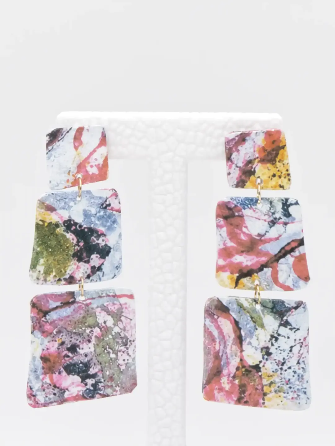 Colorful abstract three-tier dangle earrings on white display
